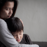A mother hugging a sick child in her lap.